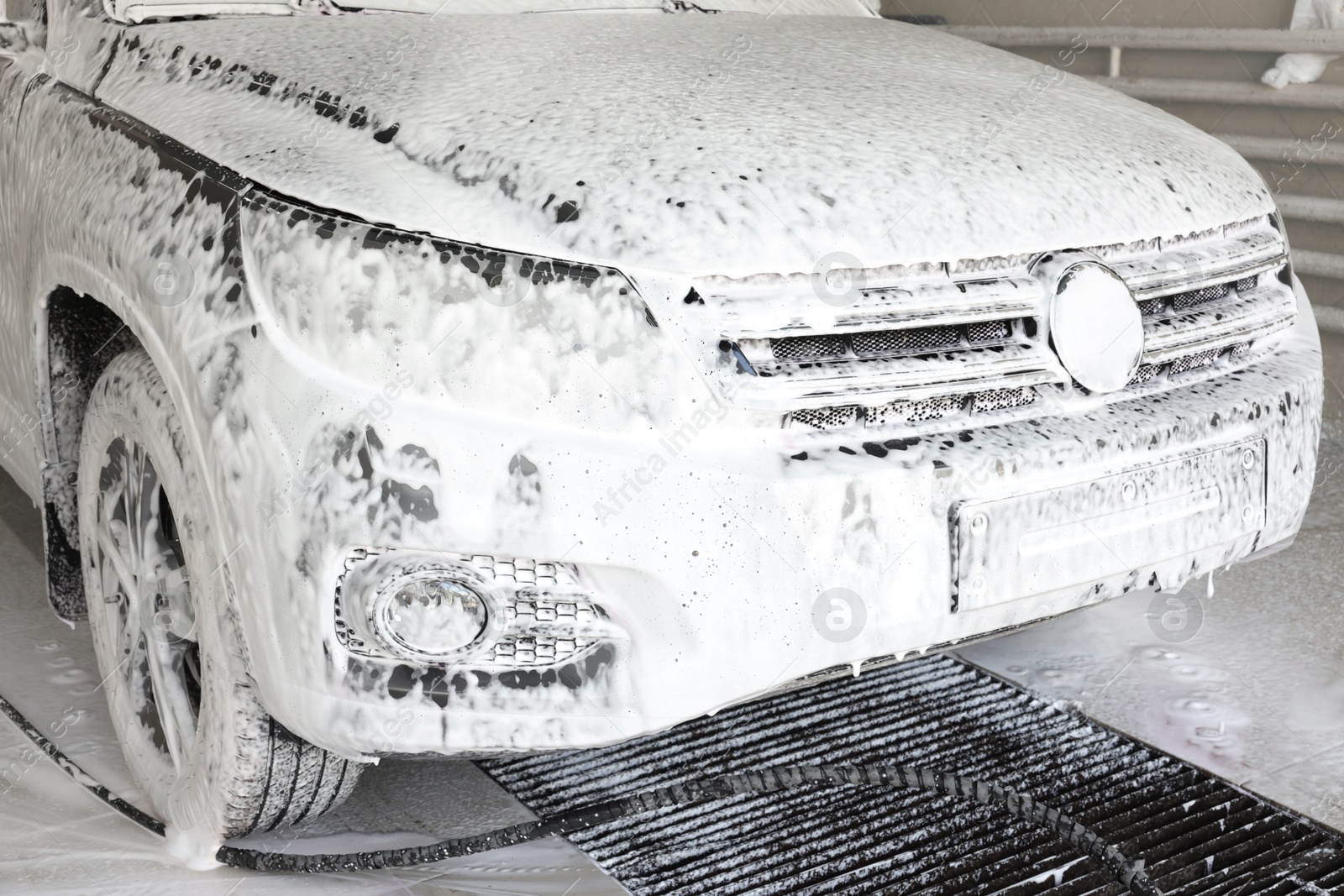 Photo of Auto covered with cleaning foam at car wash, closeup