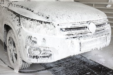 Auto covered with cleaning foam at car wash, closeup