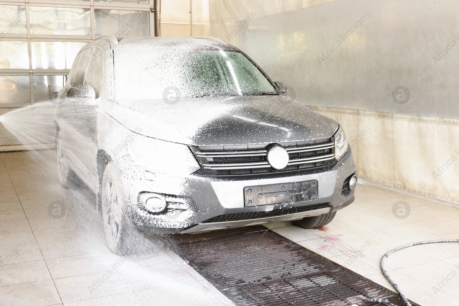 Photo of Washing auto with high pressure water jet at car wash, closeup