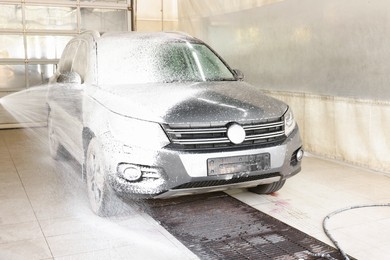 Washing auto with high pressure water jet at car wash, closeup