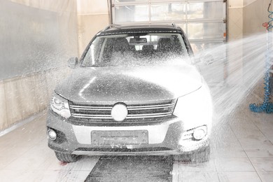 Photo of Washing auto with high pressure water jet at car wash, closeup