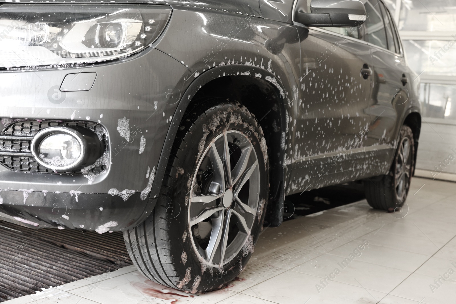 Photo of Auto covered with cleaning foam at car wash, closeup