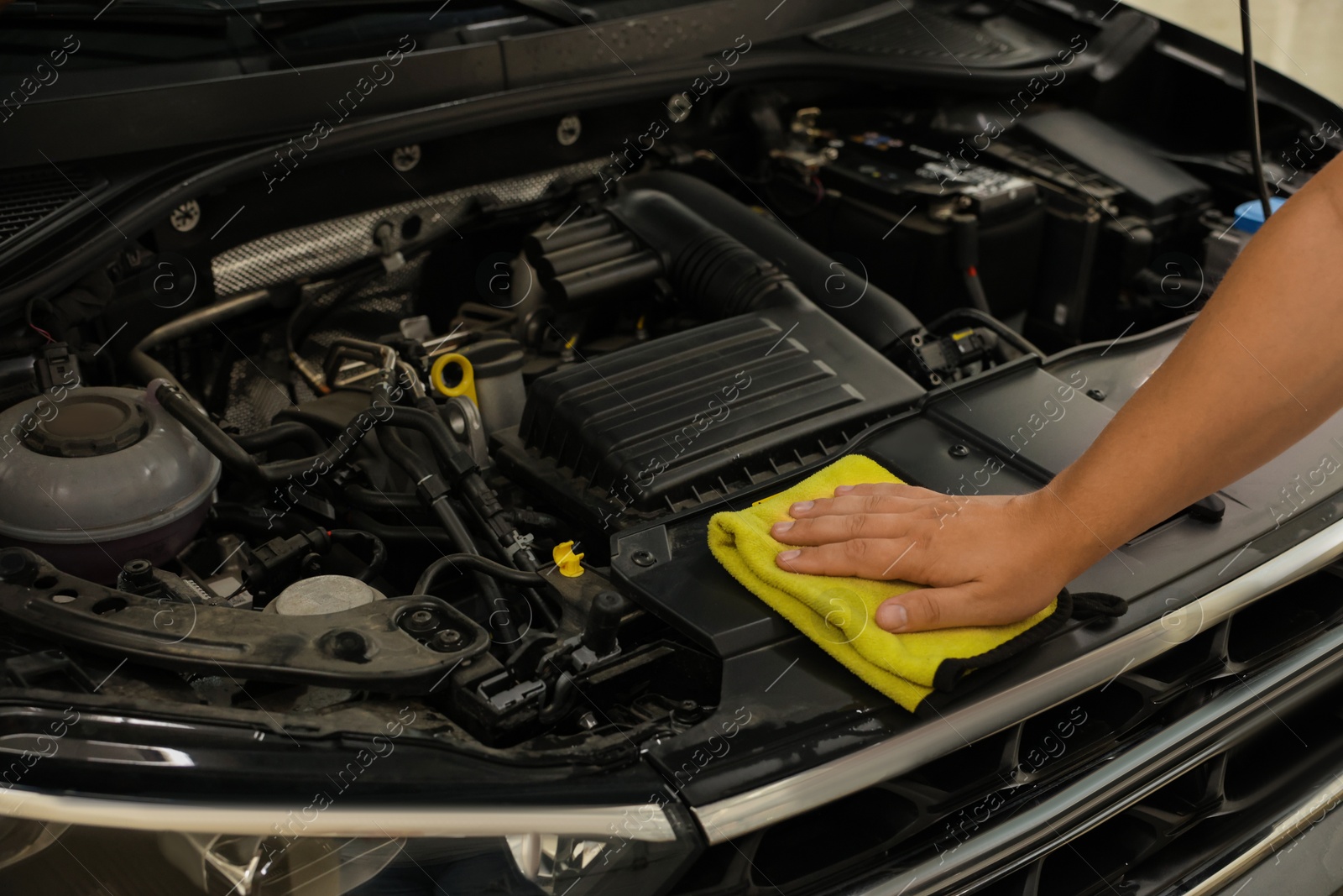 Photo of Man wiping auto engine with rag at car wash, closeup