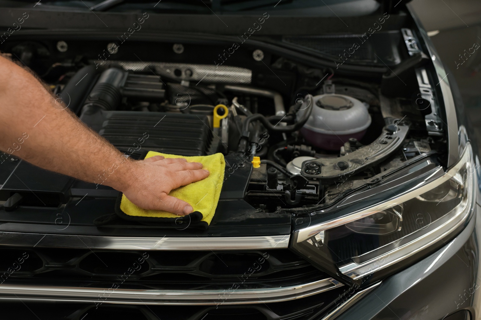 Photo of Man wiping auto engine with rag at car wash, closeup