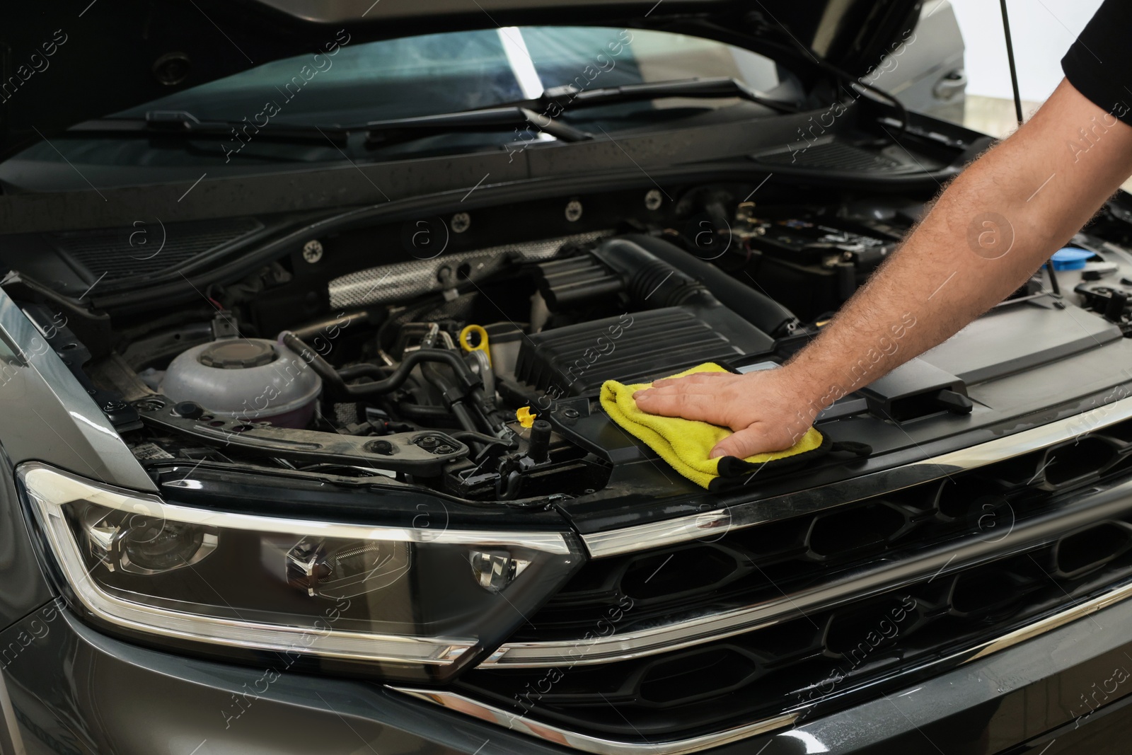 Photo of Man wiping auto engine with rag at car wash, closeup