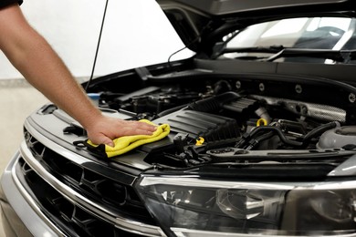 Photo of Man wiping auto engine with rag at car wash, closeup