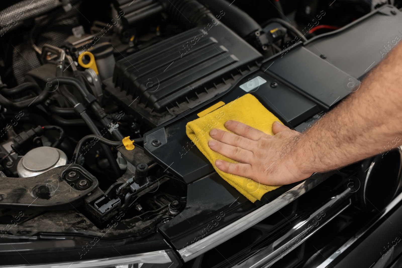 Photo of Man wiping auto engine with rag at car wash, closeup