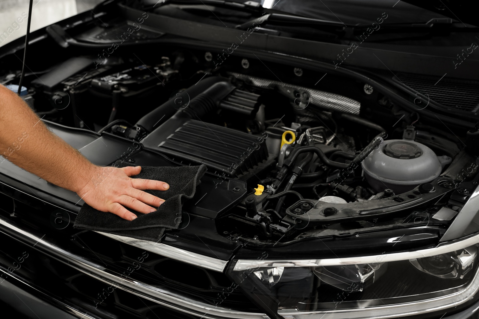 Photo of Man wiping auto engine with rag at car wash, closeup