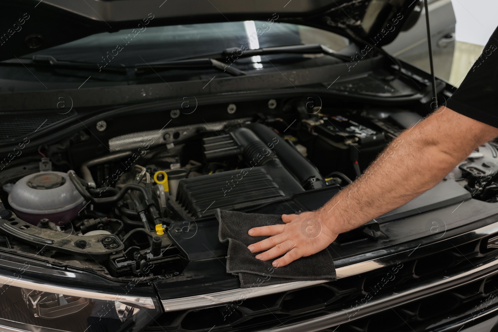 Photo of Man wiping auto engine with rag at car wash, closeup