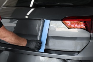 Man wiping auto with squeegee brush at car wash, closeup