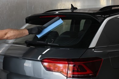 Photo of Man wiping auto with squeegee brush at car wash, closeup