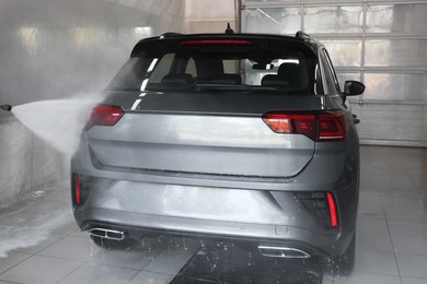 Photo of Washing auto with high pressure water jet at car wash, closeup