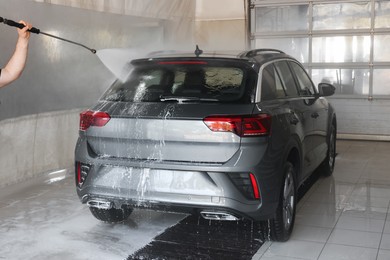 Photo of Man washing auto with high pressure water jet at car wash, closeup