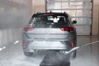 Photo of Washing auto with high pressure water jet at car wash, closeup