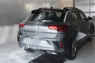 Photo of Washing auto with high pressure water jet at car wash, closeup