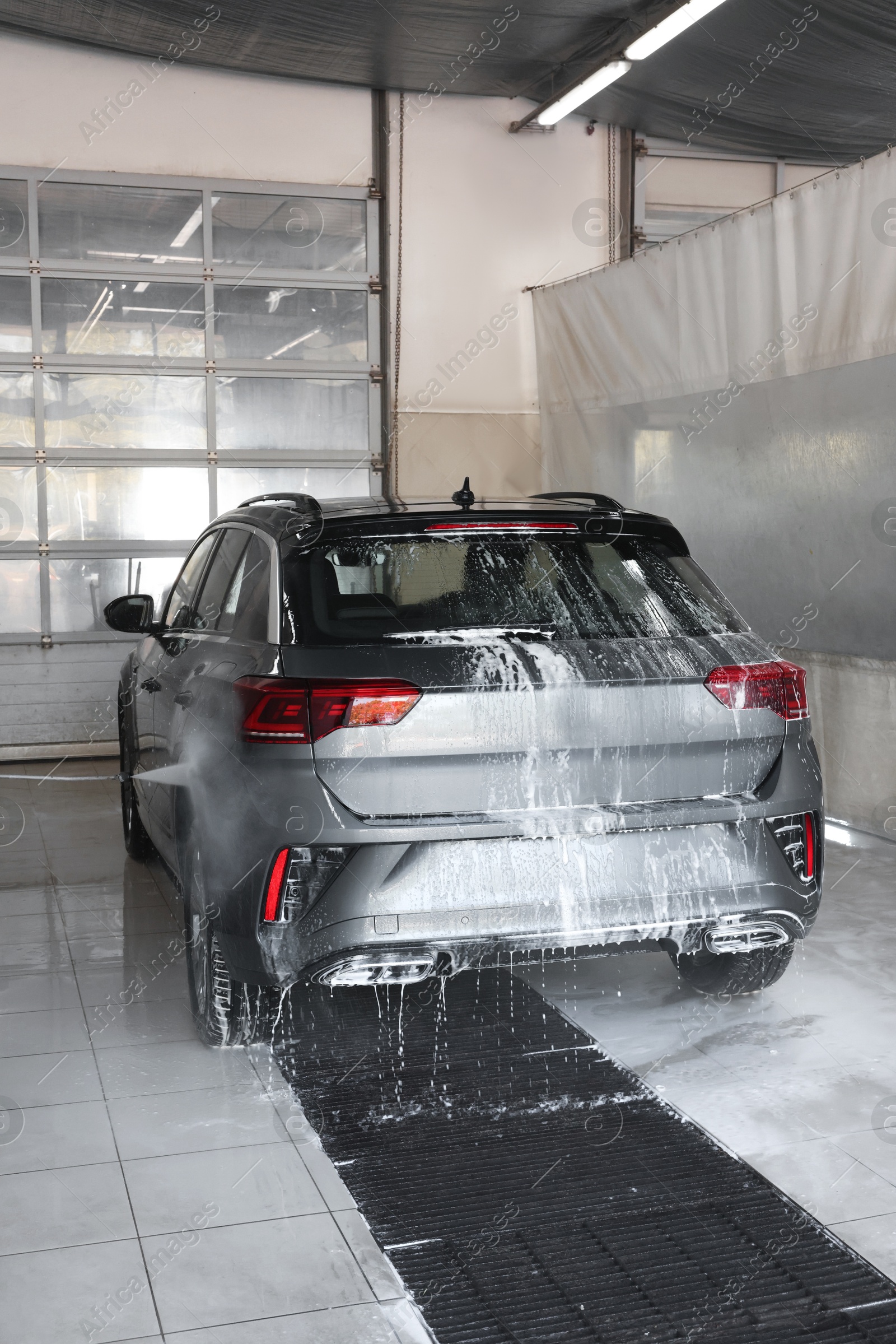 Photo of Washing auto with high pressure water jet at car wash, closeup