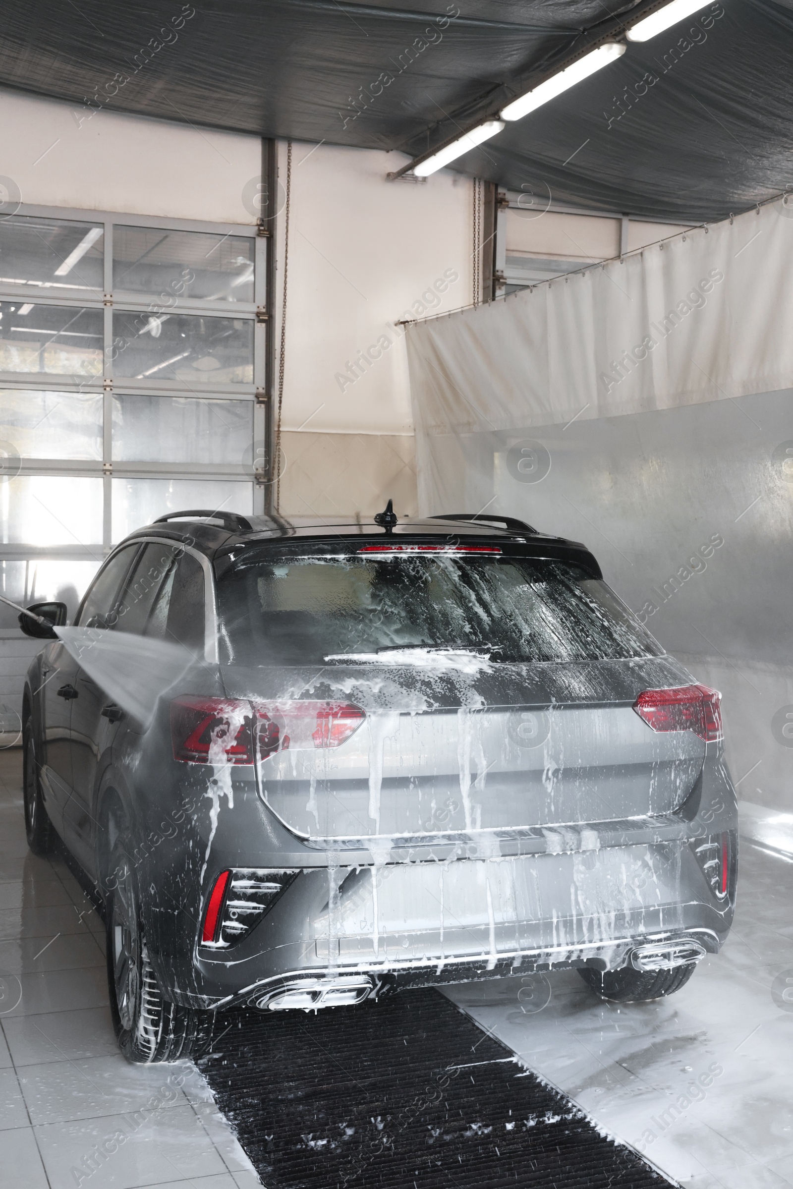 Photo of Washing auto with high pressure water jet at car wash, closeup