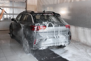 Man washing auto with high pressure water jet at car wash, closeup