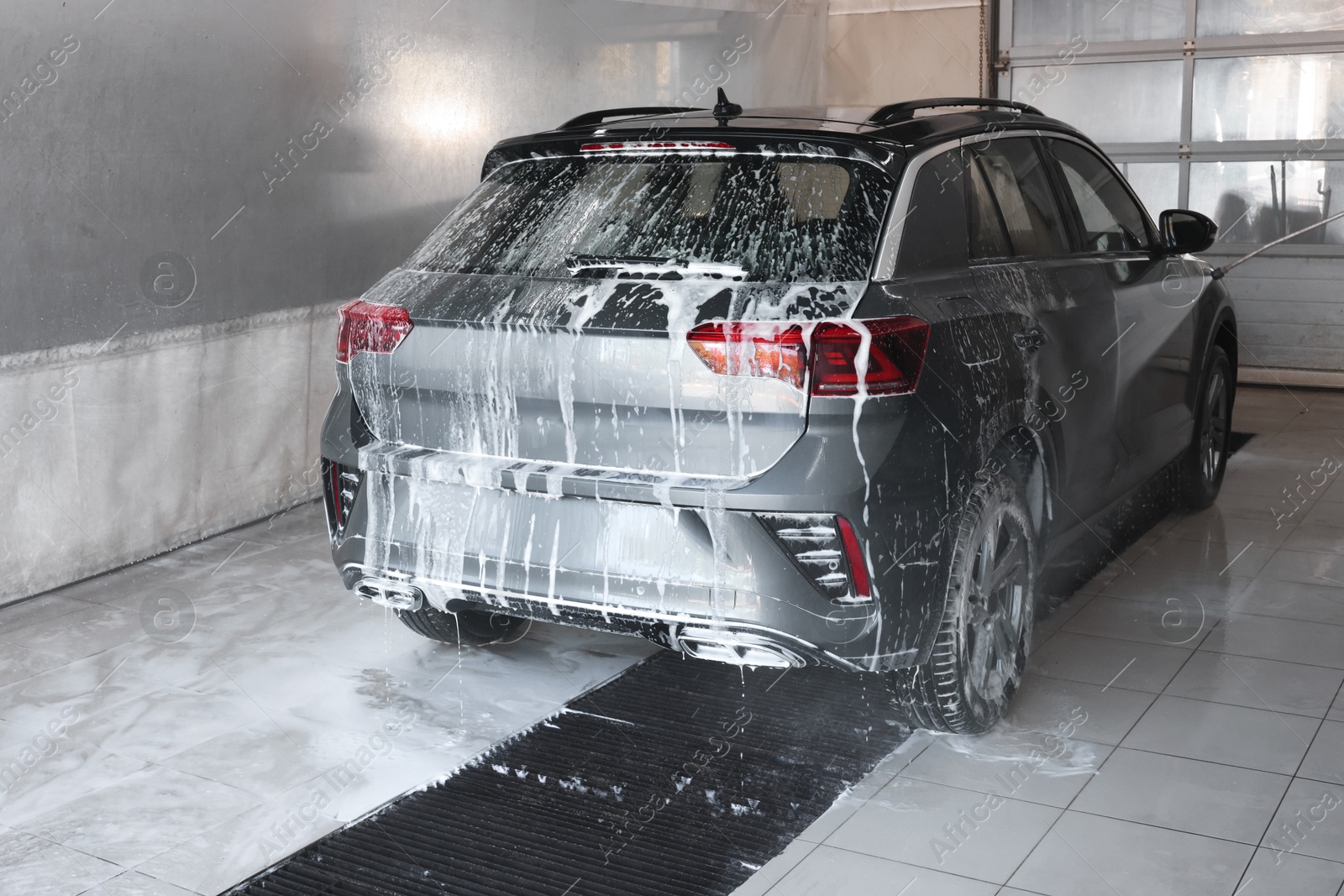 Photo of Washing auto with high pressure water jet at car wash, closeup