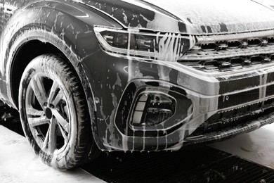 Photo of Auto covered with cleaning foam at car wash, closeup