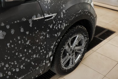 Auto covered with cleaning foam at car wash, closeup