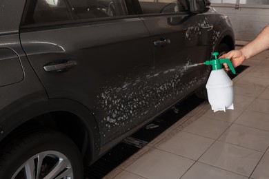 Photo of Man washing auto with sprayer at car wash, closeup