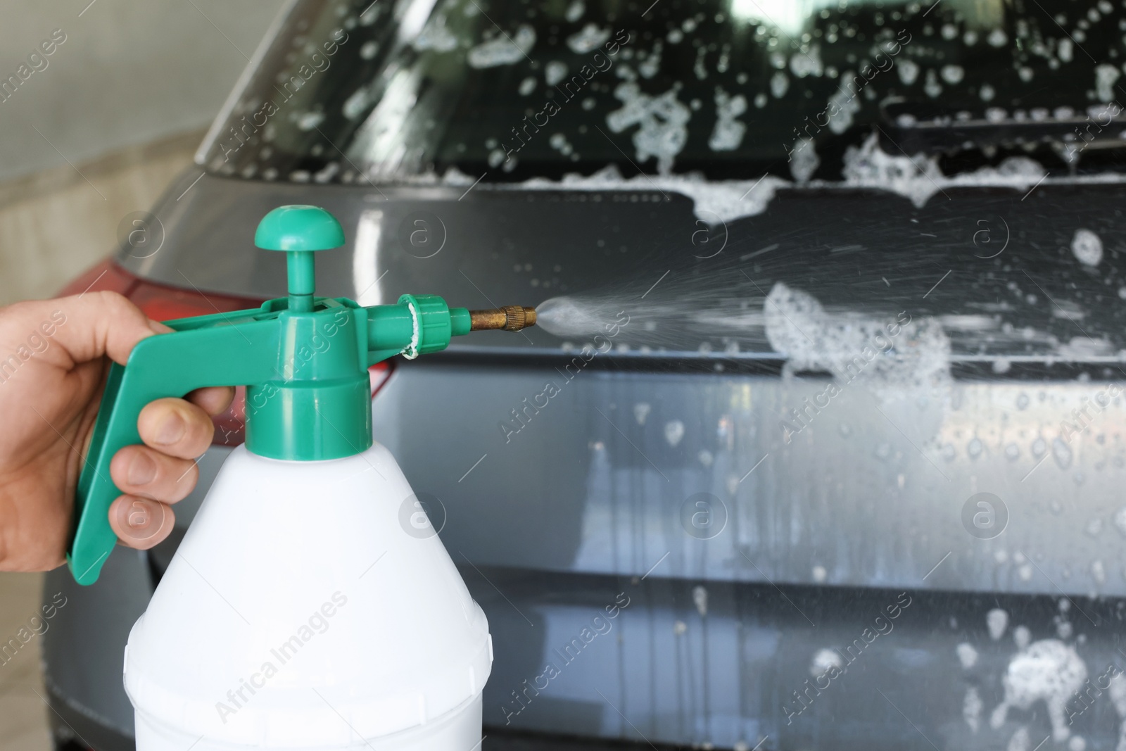 Photo of Man washing auto with sprayer at car wash, closeup