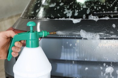 Man washing auto with sprayer at car wash, closeup