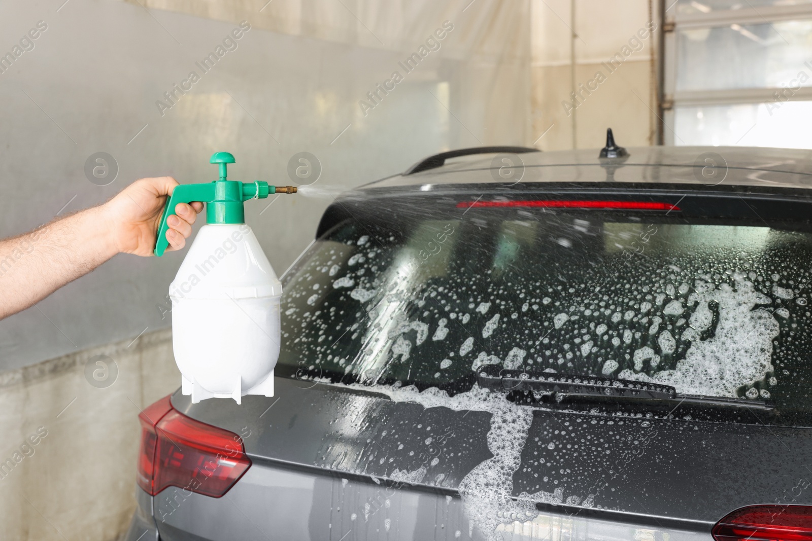 Photo of Man washing auto with sprayer at car wash, closeup