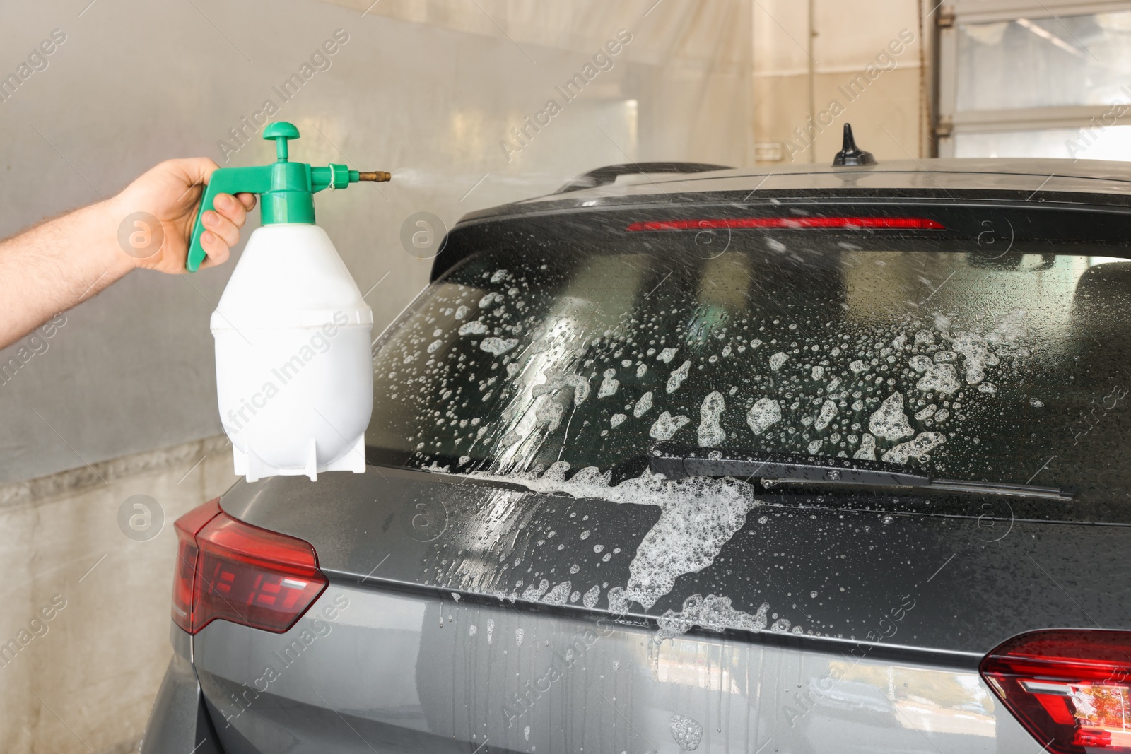 Photo of Man washing auto with sprayer at car wash, closeup