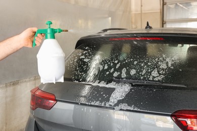 Man washing auto with sprayer at car wash, closeup