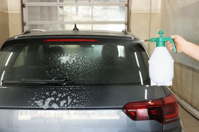 Photo of Man washing auto with sprayer at car wash, closeup