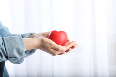 Photo of Woman holding red heart on light background, closeup