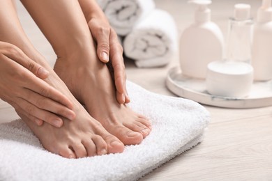 Photo of Woman touching her smooth feet on floor, closeup. Body care