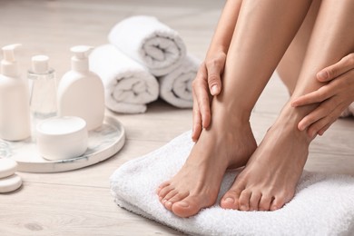 Photo of Woman touching her smooth feet on floor, closeup. Body care