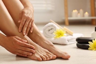 Photo of Woman touching her smooth feet on floor, closeup. Body care