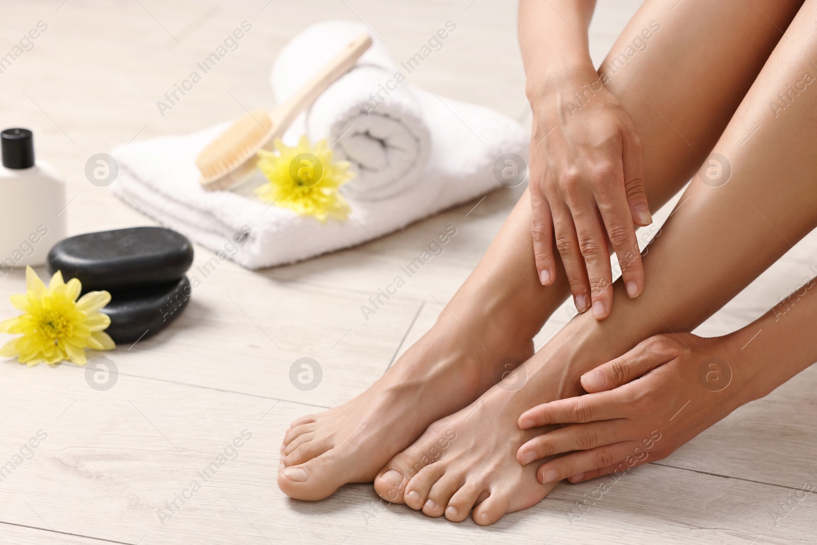 Photo of Woman touching her smooth feet on floor, closeup. Body care