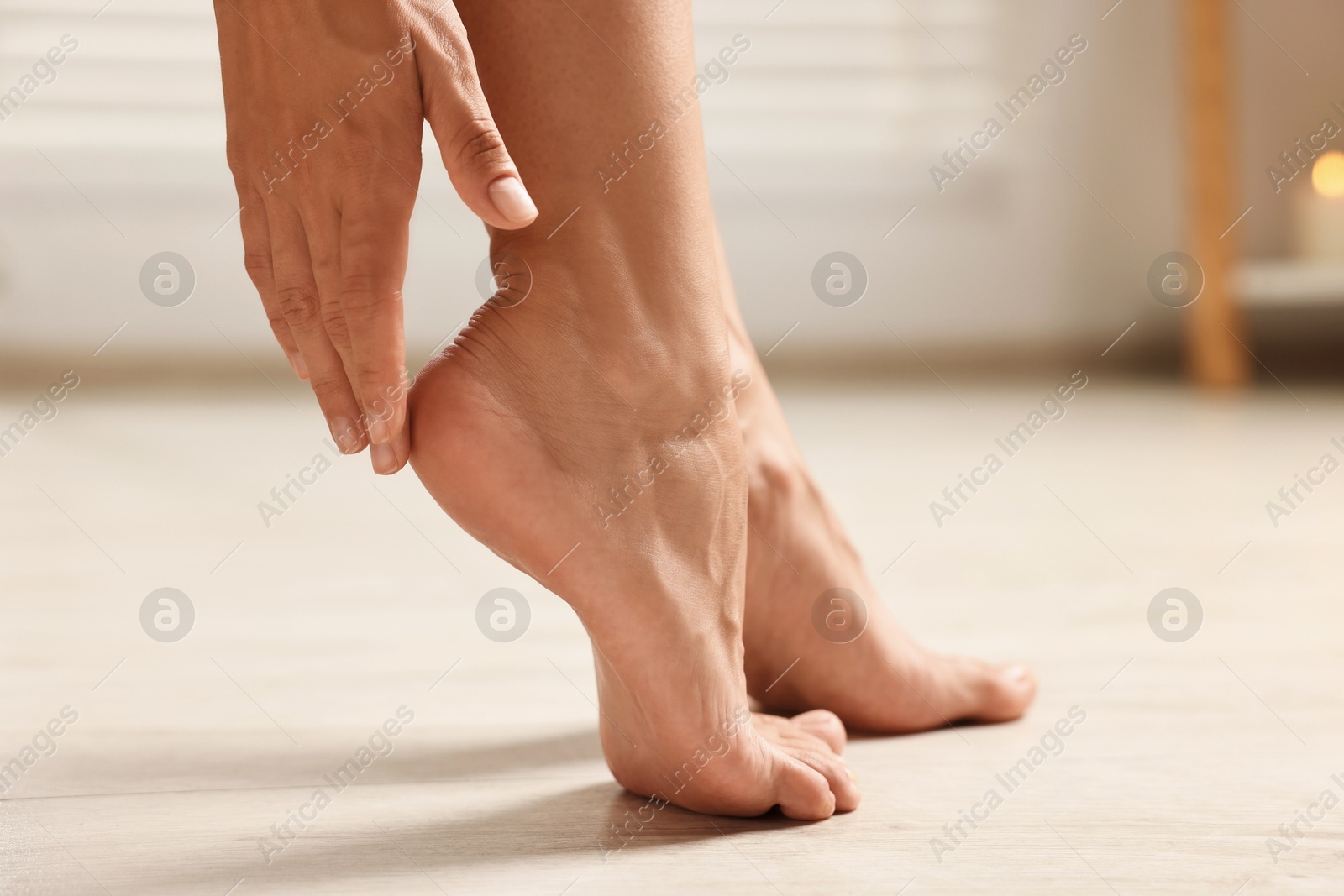 Photo of Woman touching her smooth feet on floor, closeup. Body care