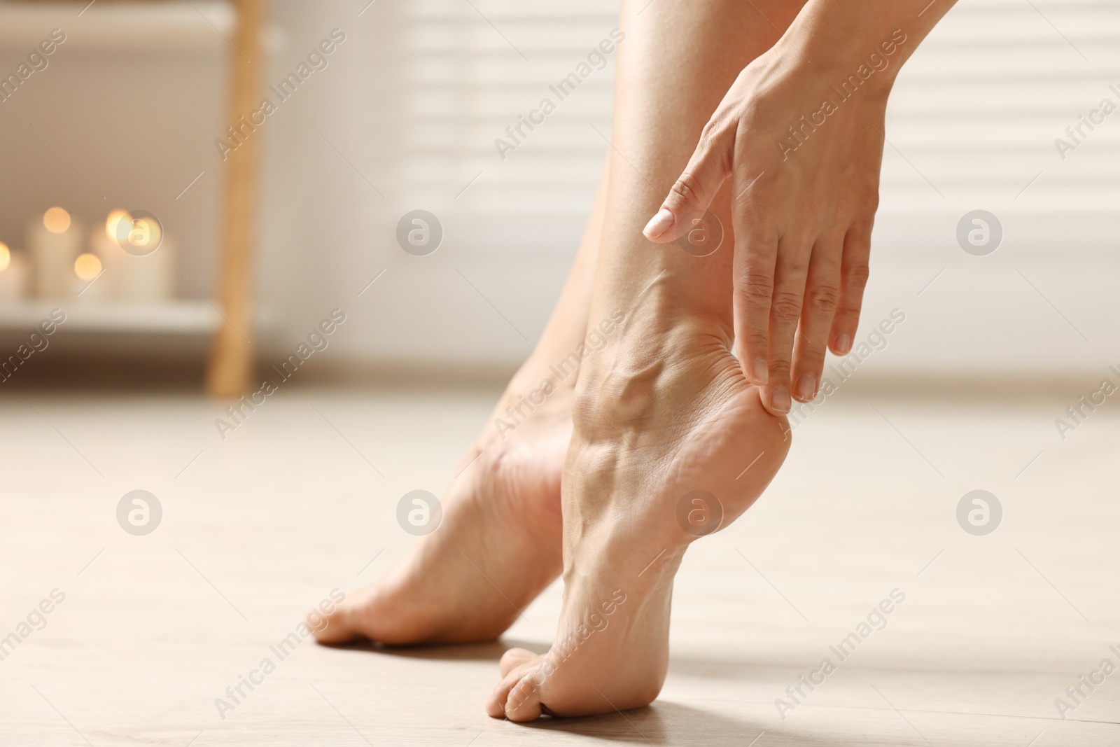 Photo of Woman touching her smooth feet on floor, closeup. Body care