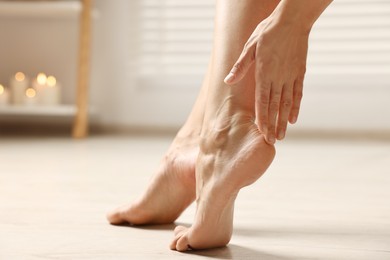 Woman touching her smooth feet on floor, closeup. Body care