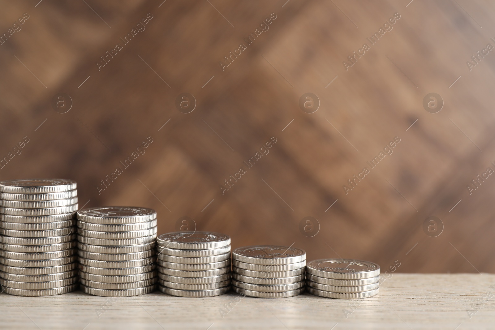 Photo of Stacked coins on light wooden table, closeup with space for text. Salary concept