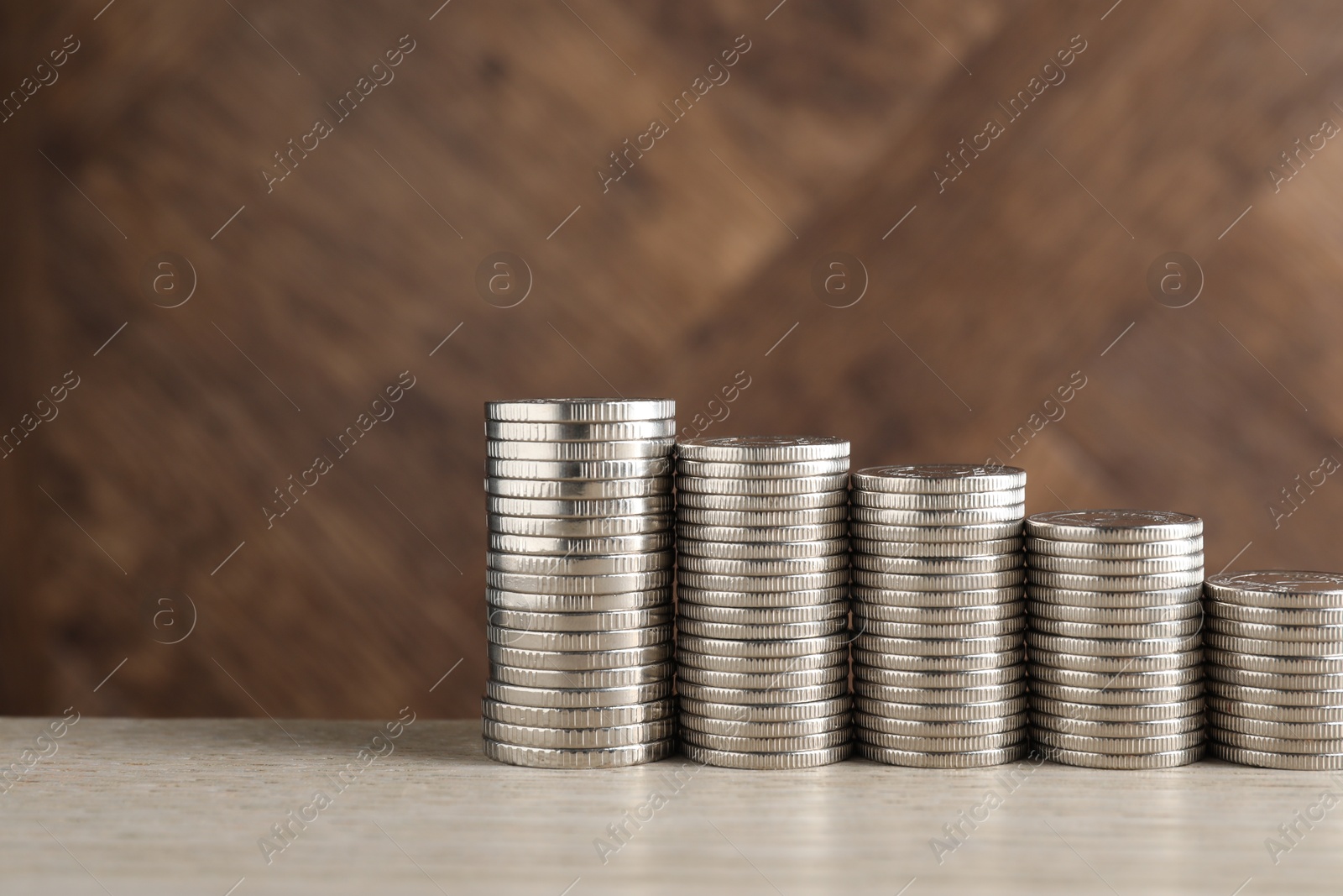 Photo of Stacked coins on light wooden table, closeup with space for text. Salary concept