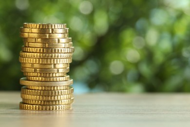 Photo of Stack of coins on light wooden table against blurred green background, closeup with space for text. Salary concept