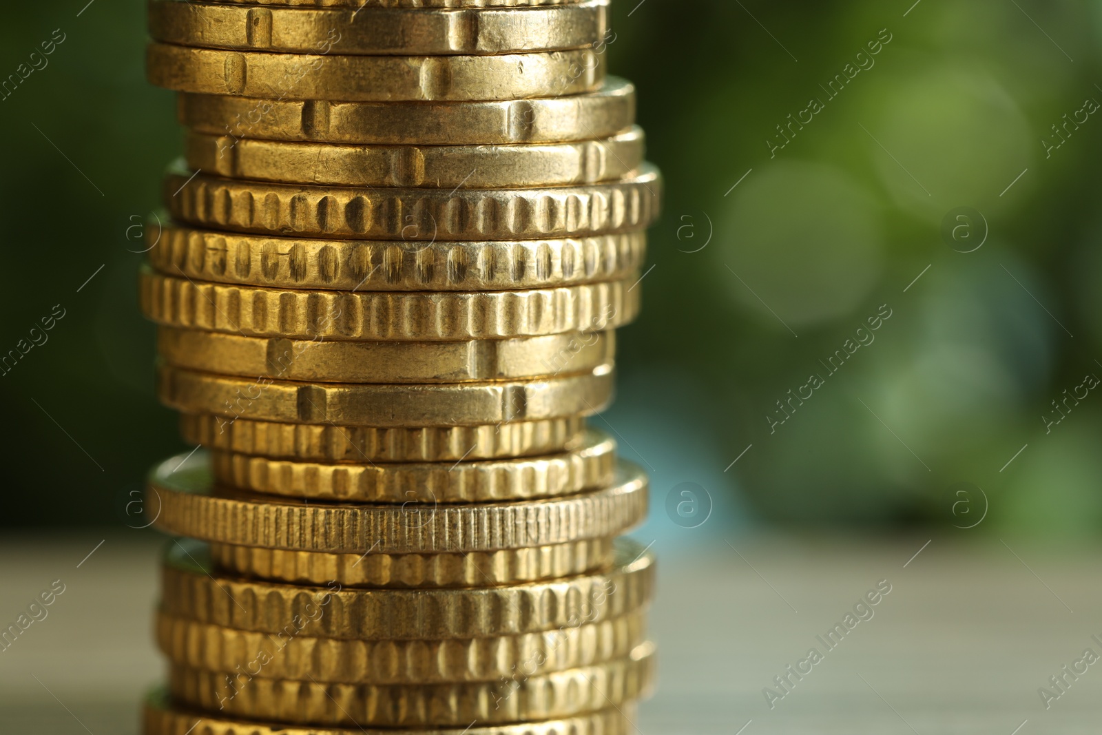 Photo of Stack of coins on blurred green background, closeup with space for text. Salary concept