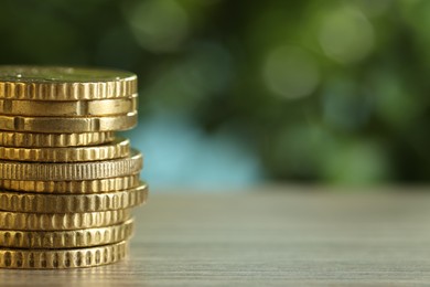 Photo of Stack of coins on light wooden table against blurred green background, closeup with space for text. Salary concept