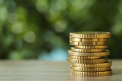 Photo of Stack of coins on light wooden table against blurred green background, closeup with space for text. Salary concept