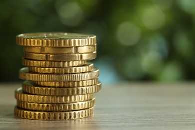 Photo of Stack of coins on light wooden table against blurred green background, closeup with space for text. Salary concept