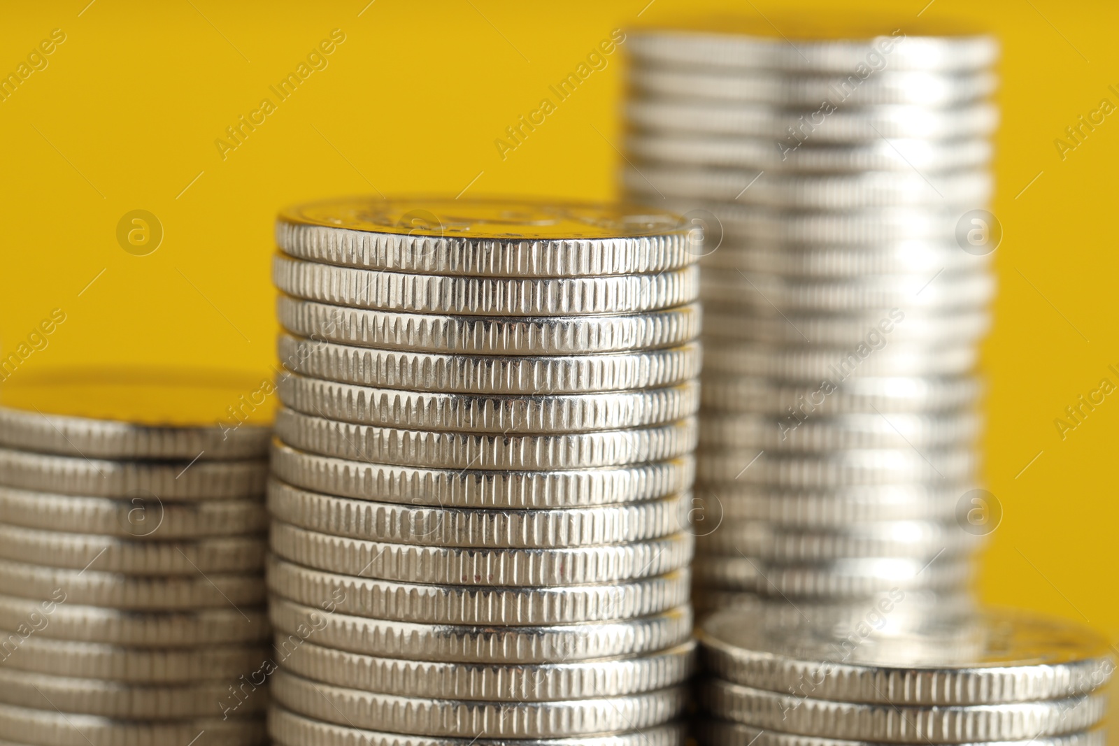 Photo of Stacked coins on yellow background, closeup. Salary concept