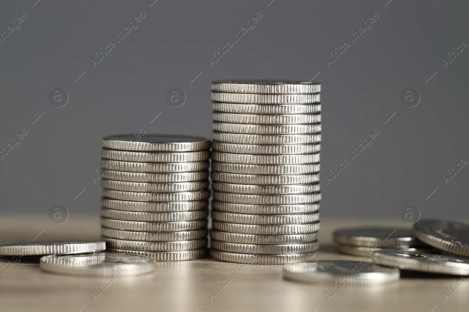 Photo of Stacked coins on wooden table against grey background, closeup. Salary concept