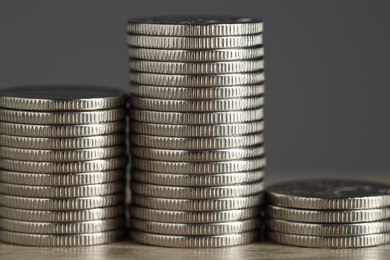 Photo of Stacked coins on wooden table against grey background, closeup. Salary concept